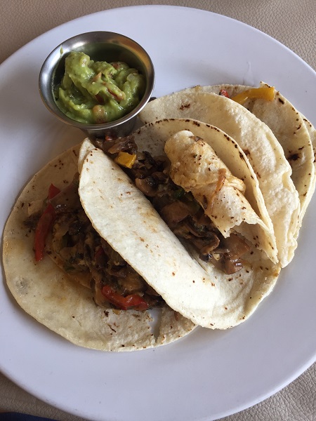 Assaggiate i tacos al pastor, tortillas di mais farcite con carne di maiale allo spiedo, servite con verdure e cipolla.