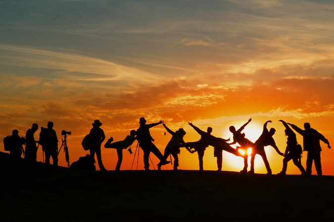 Un gruppo di persone fotografata in contro luce, simbolo dei turisti che scelgono di partire con i viaggi organizzati.